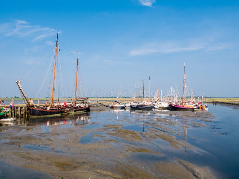 Парусники в Марине во время отлива, западный остров Schiermonnikoog Frisian, Нидерланд стоковая фотография Парусники в Марине во время отлива, западный остров Schiermonnikoog Frisian, Нидерланд стоковая фотография
