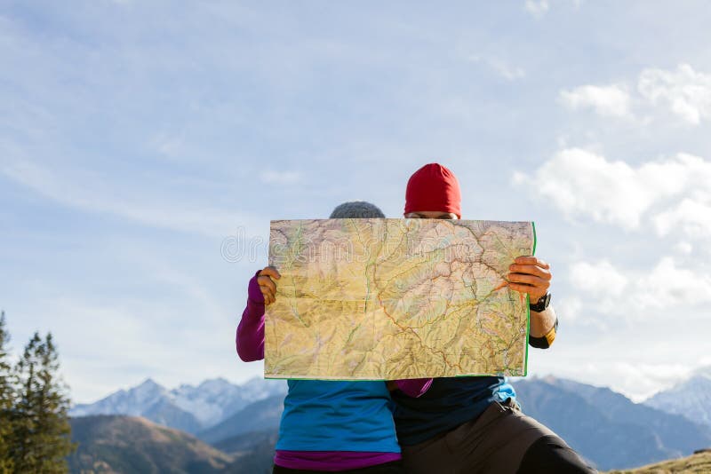 Пары hiking с картой в горах стоковое изображение Пары hiking с картой в горах стоковое изображение