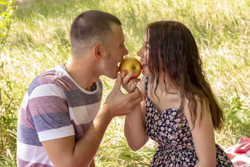 Пары в мальчике и девушке любов едят Outdoors пикника лета яблока стоковое изображение Пары в мальчике и девушке любов едят Outdoors пикника лета яблока стоковое изображение