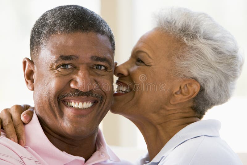 Couple relaxing indoors kissing and smiling. Couple relaxing indoors kissing and smiling.