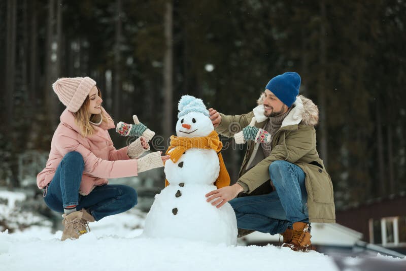 Пары делая снеговик outdoors Зима стоковая фотография rf Пары делая снеговик outdoors Зима стоковая фотография rf