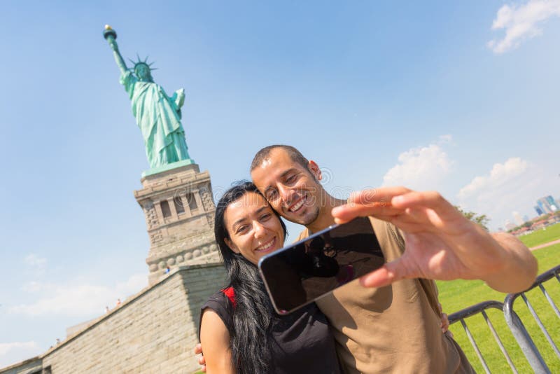 Пары принимая Selfie с статуей свободы стоковые фотографии rf Пары принимая Selfie с статуей свободы стоковые фотографии rf
