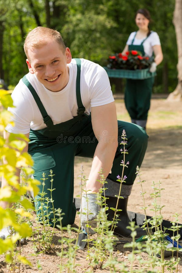 Blue collar workers in the garden planting flowers. Blue collar workers in the garden planting flowers