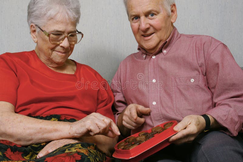 Elderly couple eating chocolates for st-valentin holiday. Elderly couple eating chocolates for st-valentin holiday