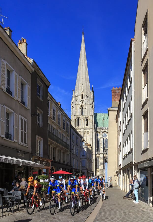 Chartres, France - October 10, 2022: The peloton rides on a small street at the south part of The Chartres Cathedral during Paris-Tour 2022. Chartres, France - October 10, 2022: The peloton rides on a small street at the south part of The Chartres Cathedral during Paris-Tour 2022