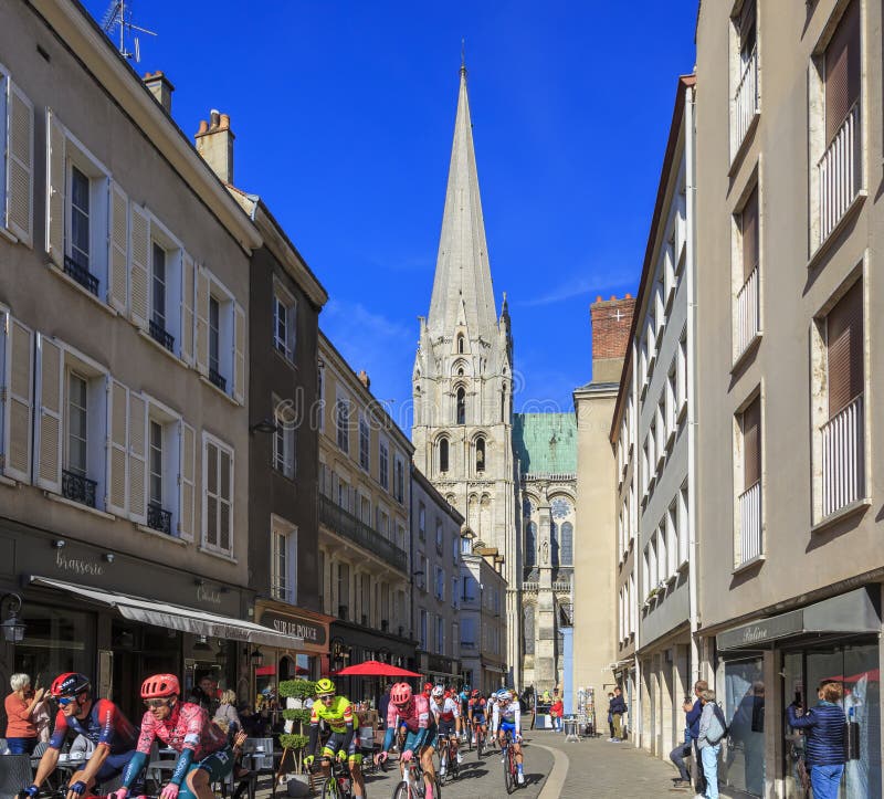 Chartres, France - October 10, 2022: The peloton rides on a small street at the south part of The Chartres Cathedral during Paris-Tour 2022. Chartres, France - October 10, 2022: The peloton rides on a small street at the south part of The Chartres Cathedral during Paris-Tour 2022