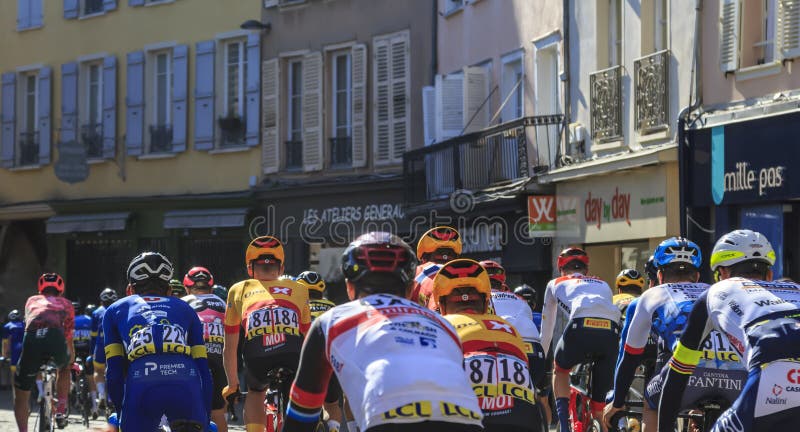 Chartres, France - October 10, 2022: Rear view of the peloton riding on a small street at the south part of The Chartres Cathedral during Paris-Tour 2022. Chartres, France - October 10, 2022: Rear view of the peloton riding on a small street at the south part of The Chartres Cathedral during Paris-Tour 2022