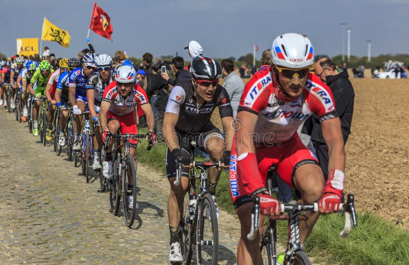 Carrefour de l`Arbre,France-April 13,2014: The peloton riding on the famous cobblestone sector Carrefour de l`Arbre in Camphin-en-Pévèle town during the 2014 edition of Paris-Roubaix cycling race. Carrefour de l`Arbre,France-April 13,2014: The peloton riding on the famous cobblestone sector Carrefour de l`Arbre in Camphin-en-Pévèle town during the 2014 edition of Paris-Roubaix cycling race