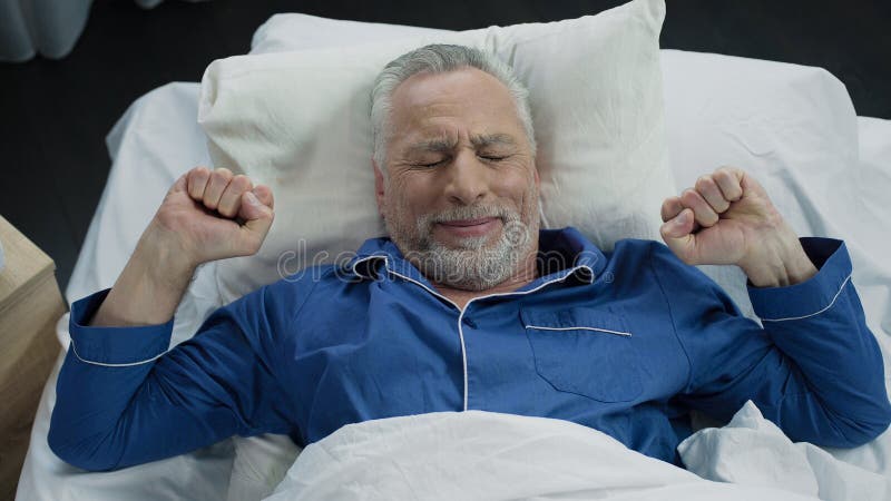 Pensioner stretching in his bed after awakening in the morning, healthy sleep, stock footage. Pensioner stretching in his bed after awakening in the morning, healthy sleep, stock footage