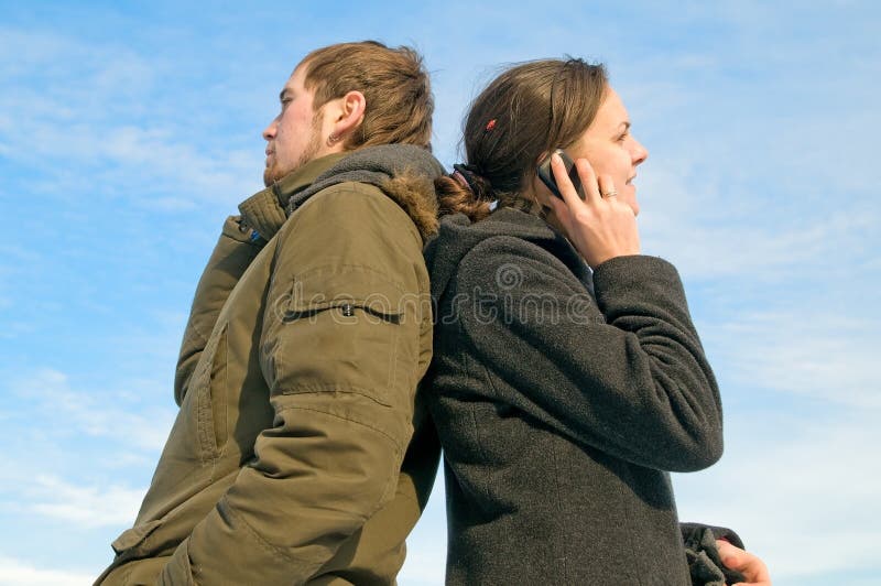 Boy and girl backs to each other and talk on the phone. Boy and girl backs to each other and talk on the phone.