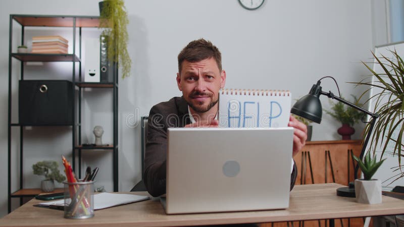 перегруженный рабочий бизнесмен, работающий над ноутбуком, показывающий записную книжку с помощью текста справки акции видеоматериалы