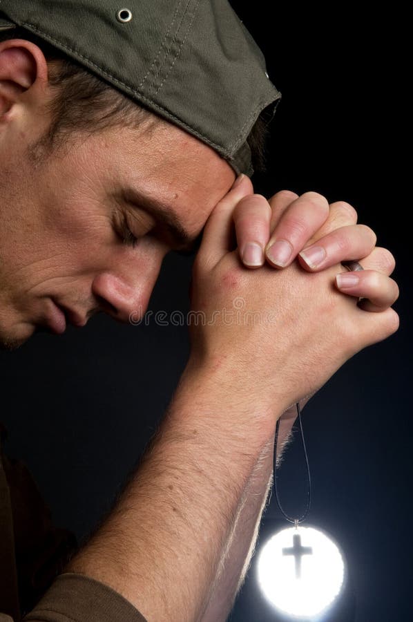 Praying man holding a cross in front of a bright light. Praying man holding a cross in front of a bright light.