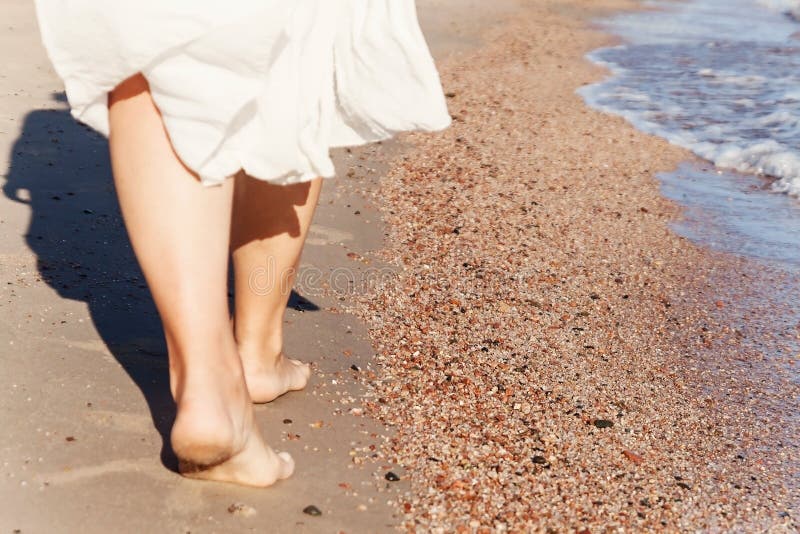 Vacation travel - woman leg closeup walking on white sand relaxing in beach cover-up pareo beachwear. and tanned legs. Sunmmer holidays, weight loss or epilation, pedicure concept. Vacation travel - woman leg closeup walking on white sand relaxing in beach cover-up pareo beachwear. and tanned legs. Sunmmer holidays, weight loss or epilation, pedicure concept.