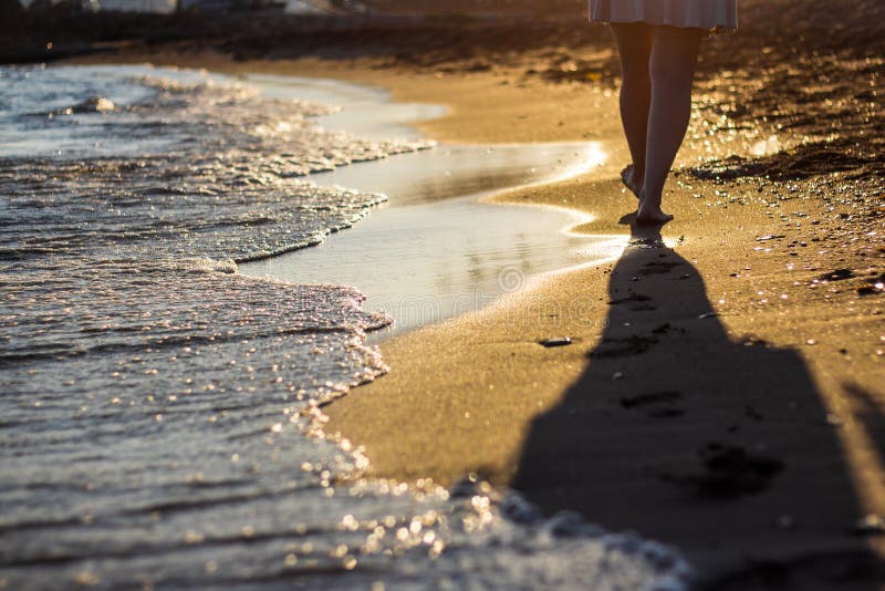 Перемещение пляжа - женщина идя на песчаный пляж покидая следам ноги i