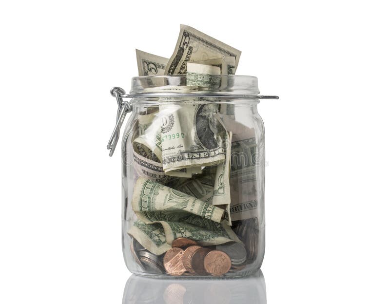 A tip jar or jar for savings filled over the top with American coins and bills. A tip jar or jar for savings filled over the top with American coins and bills.