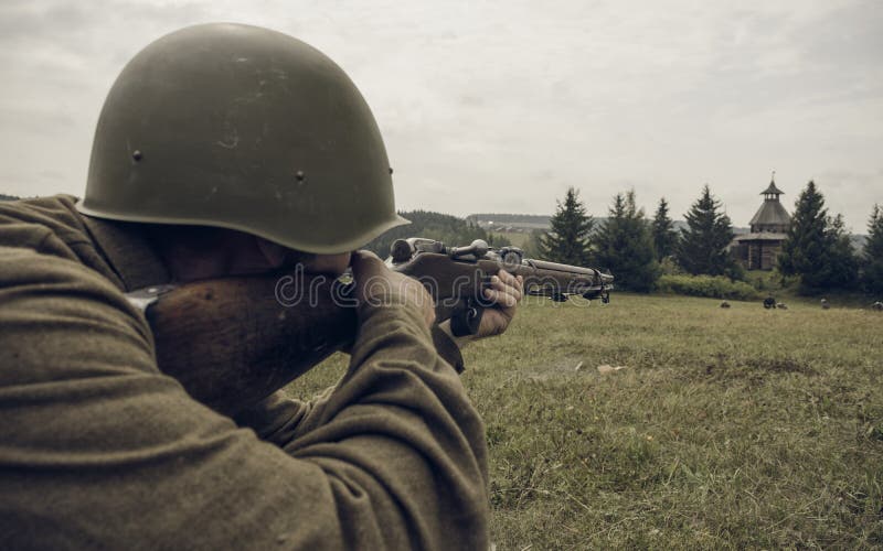 ПЕРМЬ, РОССИЯ - 30-ОЕ ИЮЛЯ 2016: Исторический reenactment Второй Мировой Войны, лето, 1942 Советский солдат направляя винтовку стоковая фотография rf