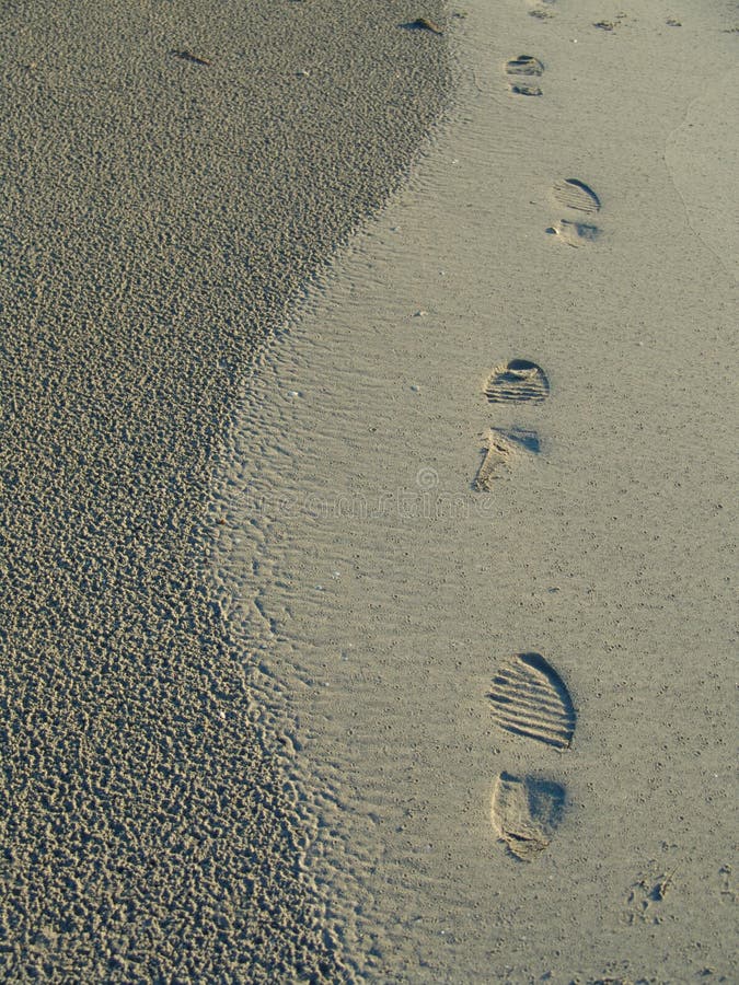 A set of footprints embedded in the sand next to the beach. A set of footprints embedded in the sand next to the beach