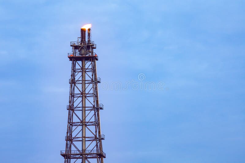 Печная труба башни нефтеперерабатывающего предприятия с огнем на верхней части на голубом небе облака стоковое изображение Печная труба башни нефтеперерабатывающего предприятия с огнем на верхней части на голубом небе облака стоковое изображение