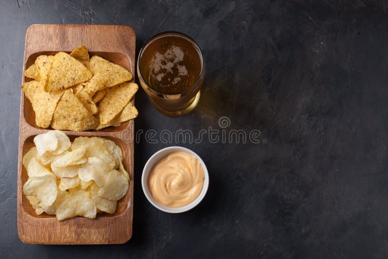 Пиво в крупном плане стекел на конкретной таблице Пиво и закуски обломоки и nachos в деревянном шаре с souce сыра Взгляд сверху C стоковые изображения rf Пиво в крупном плане стекел на конкретной таблице Пиво и закуски обломоки и nachos в деревянном шаре с souce сыра Взгляд сверху C стоковые изображения rf