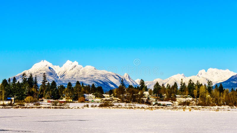 The snow covered peaks of the Golden Ears mountain and Mount Robie Reid behind the town of Fort Langley in the Fraser Valley of British Columbia, Canada on a cold winter day and snow covered fields. The snow covered peaks of the Golden Ears mountain and Mount Robie Reid behind the town of Fort Langley in the Fraser Valley of British Columbia, Canada on a cold winter day and snow covered fields