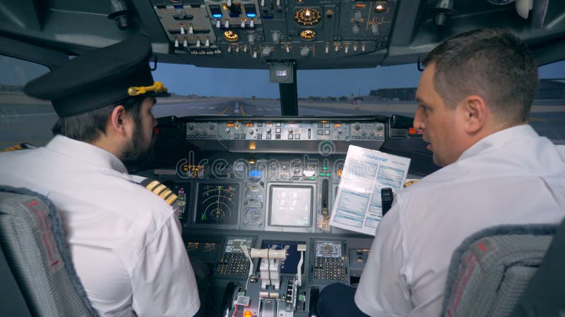 Пилоты смотрят на бумагу с инструкциями, вид сзади