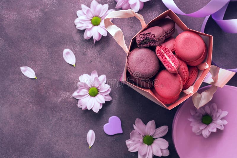 Пинк и пурпурный конец-вверх macaroon в бумажном мешке подарка на пурпурной предпосылке украшенной с цветками Взгляд сверху, селе стоковое изображение rf Пинк и пурпурный конец-вверх macaroon в бумажном мешке подарка на пурпурной предпосылке украшенной с цветками Взгляд сверху, селе стоковое изображение rf