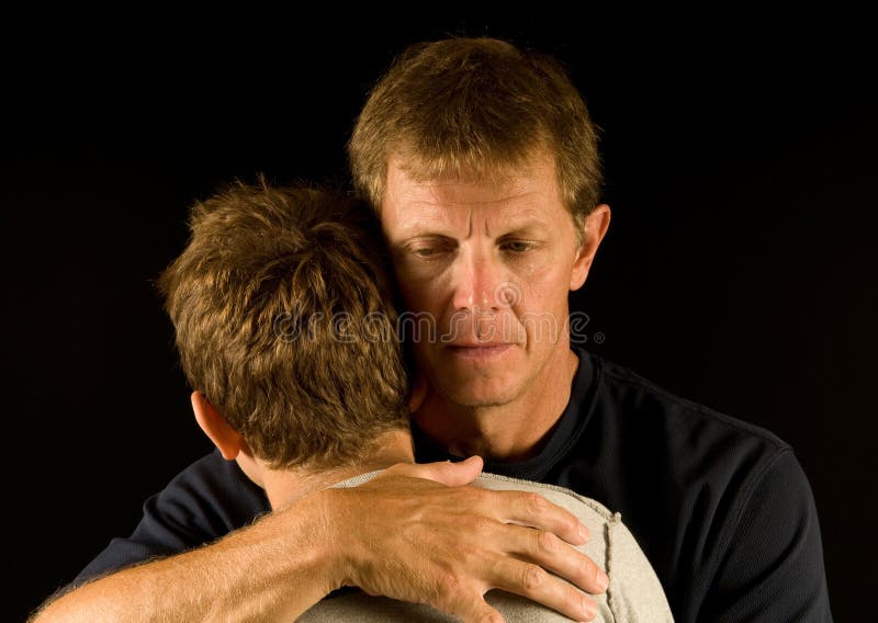 Emotional portrait of father, tear on his cheek, hugging/comforting his son. Emotional portrait of father, tear on his cheek, hugging/comforting his son.