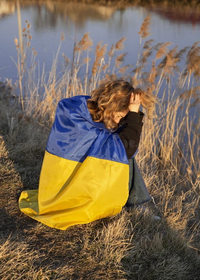 плачущая несчастная молодая патриотка. в отчаянии, завернутый в украинский флаг стоковое изображение
