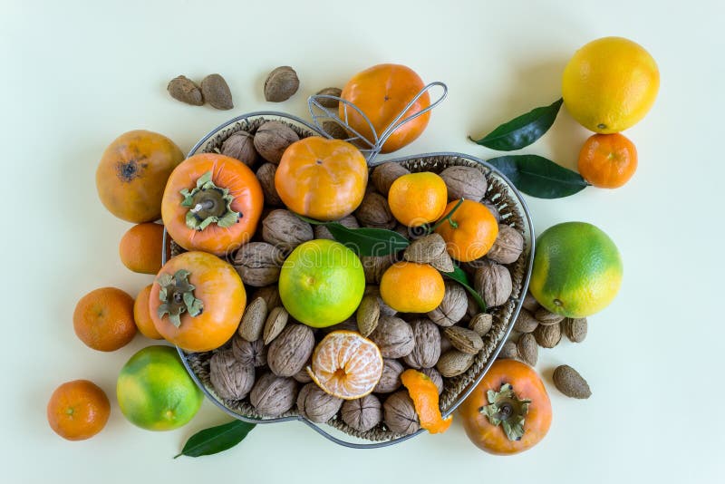 Плетеная корзина заполненная с гайками, tangerines и хурмами стоковые фотографии rf Плетеная корзина заполненная с гайками, tangerines и хурмами стоковые фотографии rf