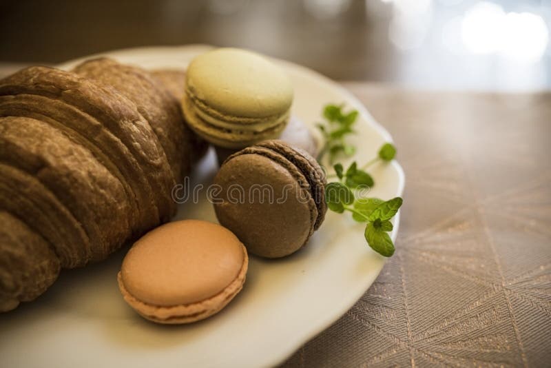 Плита с свеже испеченным очень вкусным круассаном и покрашенным macaroon стоковые изображения Плита с свеже испеченным очень вкусным круассаном и покрашенным macaroon стоковые изображения
