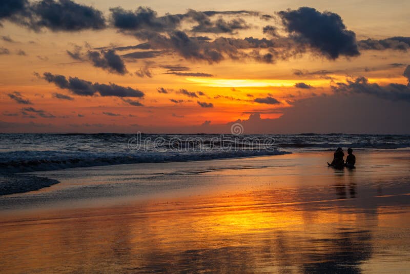 Пляж Pantai Berawa Berawa на заходе солнца Силуэты 2 людей сидя в приливе Canggu, Бали, Индонезия стоковые фото Пляж Pantai Berawa Berawa на заходе солнца Силуэты 2 людей сидя в приливе Canggu, Бали, Индонезия стоковые фото