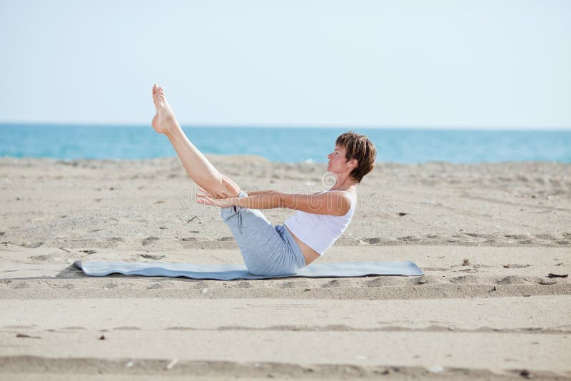 Woman doing fitness exercise on beach on a sunny day. Woman doing fitness exercise on beach on a sunny day