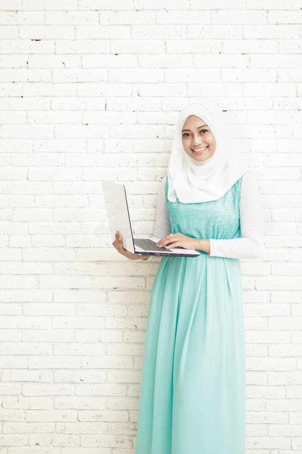 положение hijab азиатской молодой женщины нося пока держащ компьтер-книжку стоковые фото положение hijab азиатской молодой женщины нося пока держащ компьтер-книжку стоковые фото