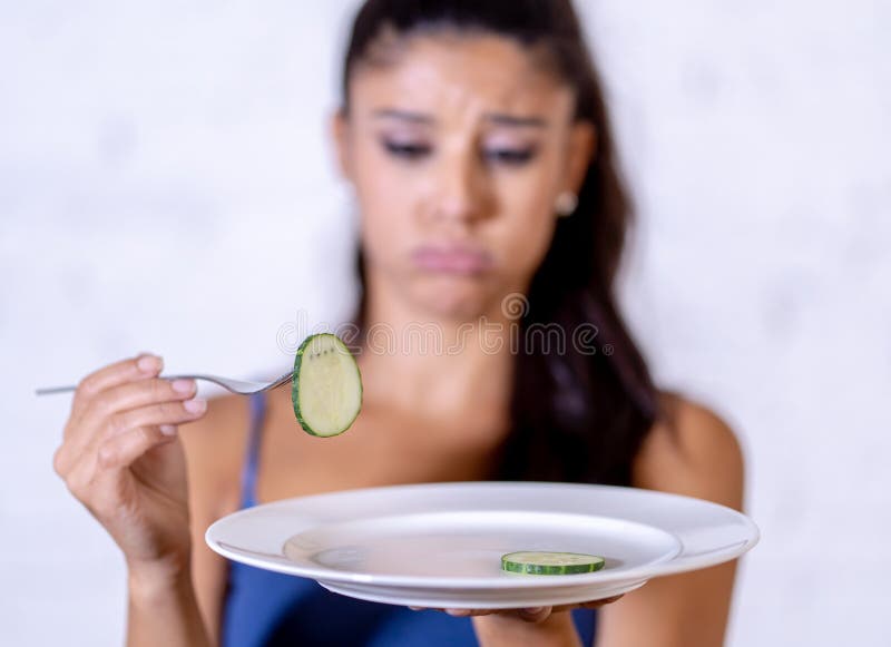 Подавленная dieting женщина держа людей смотря малый зеленый овощ на пустой плите стоковая фотография rf Подавленная dieting женщина держа людей смотря малый зеленый овощ на пустой плите стоковая фотография rf