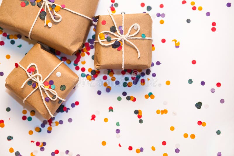 Подарочные коробки обернутые в бумаге kraft с confetti на белом backgro стоковое изображение rf Подарочные коробки обернутые в бумаге kraft с confetti на белом backgro стоковое изображение rf