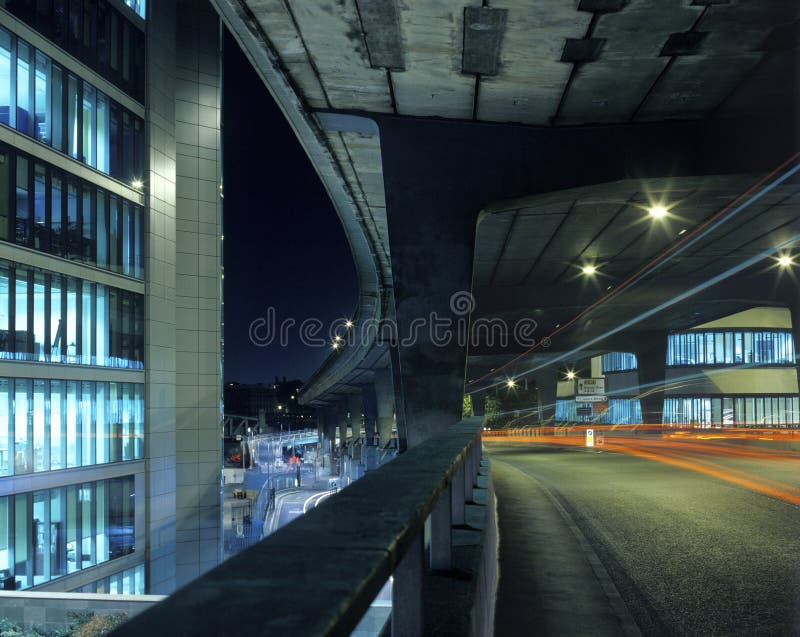 Architectural shot of a highway underpass and buildings with light trails from a moving vehicle. Architectural shot of a highway underpass and buildings with light trails from a moving vehicle