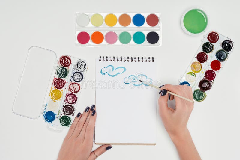подрезанное изображение женского чертежа художника paintbrush в учебнике на белой таблице с красочным стоковые изображения rf подрезанное изображение женского чертежа художника paintbrush в учебнике на белой таблице с красочным стоковые изображения rf