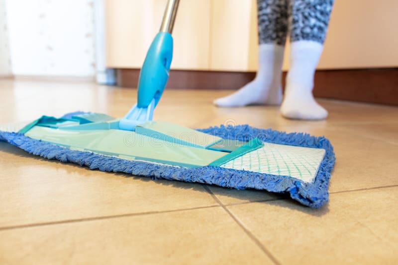 Подрезанное изображение красивой молодой женщины используя голубой mop пока очищающ пол в кухне стоковые фото Подрезанное изображение красивой молодой женщины используя голубой mop пока очищающ пол в кухне стоковые фото