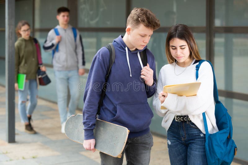 Teenage boy and girl discuss homework after college lessons on sunny spring day. Teenage boy and girl discuss homework after college lessons on sunny spring day