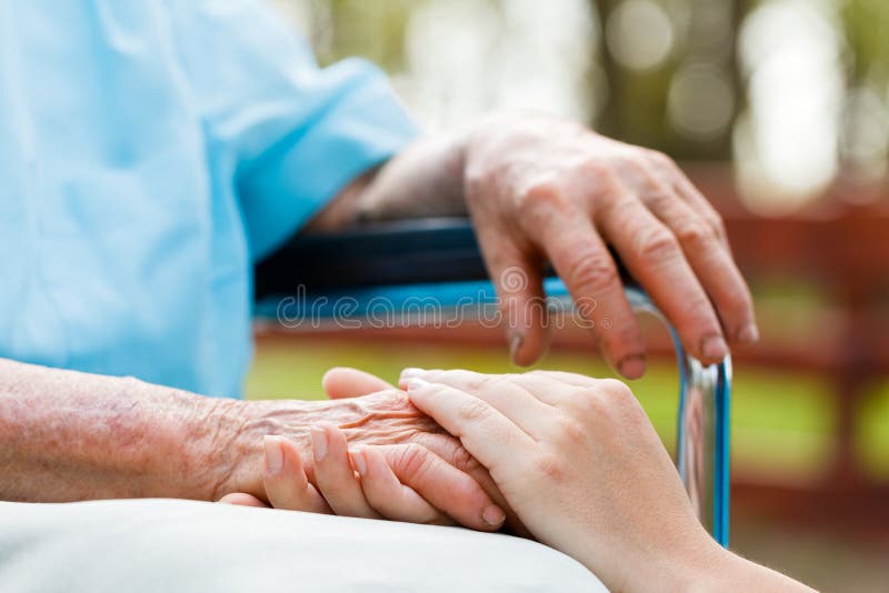 Doctor holding elderly womans hand, who is sitting in wheelchair. Doctor holding elderly womans hand, who is sitting in wheelchair.