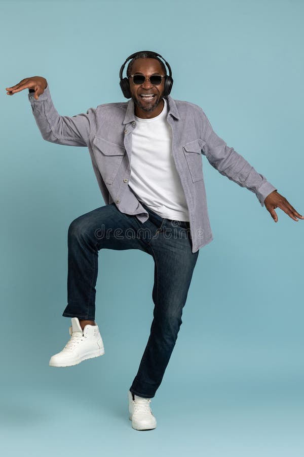 позитивный бородатый темнокожий мужчина в наушниках танцует, движется к музыке. стоковая фотография rf