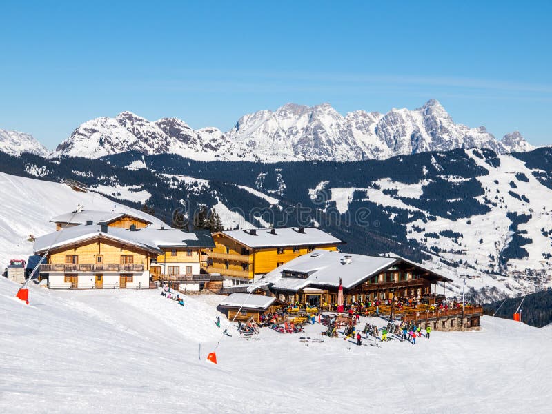 Покатая хата горы лыжи наклона и apres с террасой ресторана в зиме Saalbach Hinterglemm Leogang прибегает, Tirol стоковое изображение rf Покатая хата горы лыжи наклона и apres с террасой ресторана в зиме Saalbach Hinterglemm Leogang прибегает, Tirol стоковое изображение rf