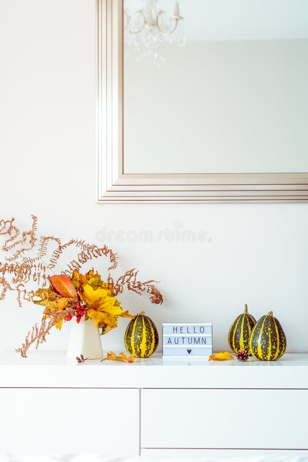 Поле с текстом HELLO AUTUMN, декоративные полосатые насосы и ваза с букетом падающих листьев и паром на белой груди, стол стоковые фотографии rf