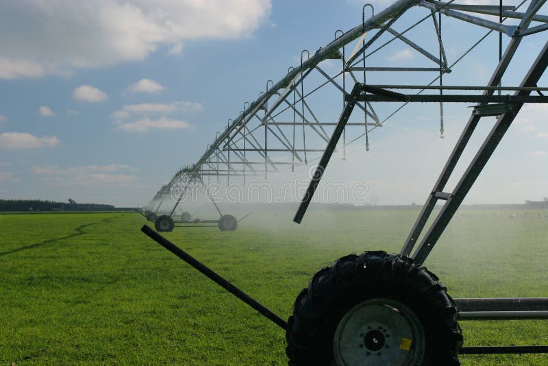 Large centre pivot irrigation system running on an open plains dairy farm in Canterbury, New Zealand. Water droplets all over the place, Sheep just visible behind mist at 100%. Large centre pivot irrigation system running on an open plains dairy farm in Canterbury, New Zealand. Water droplets all over the place, Sheep just visible behind mist at 100%.