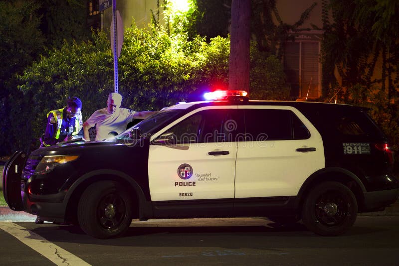 A police SUV with flashing lights blocks an intersection at Hollywood Boulevard in Los Angeles at night. A police SUV with flashing lights blocks an intersection at Hollywood Boulevard in Los Angeles at night
