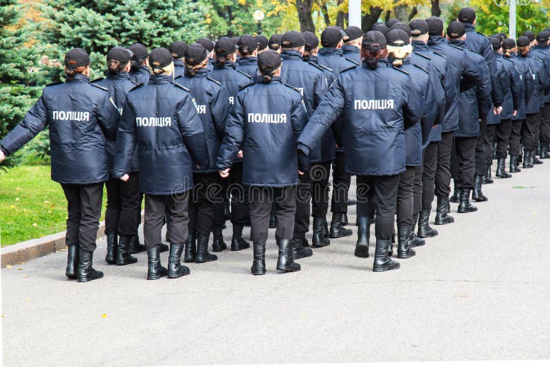 Полицейскии в форме с полицией надписи в украинце, идут вдоль улицы в городе Украине Dnipro стоковая фотография Полицейскии в форме с полицией надписи в украинце, идут вдоль улицы в городе Украине Dnipro стоковая фотография