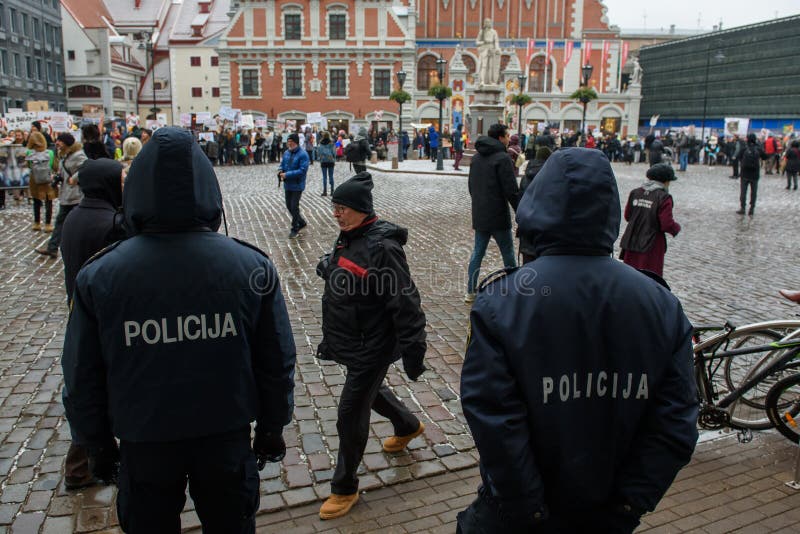 2 полицейского стоя перед толпой с участниками от „марта для животных в Риге, Латвии стоковая фотография rf 2 полицейского стоя перед толпой с участниками от „марта для животных в Риге, Латвии стоковая фотография rf