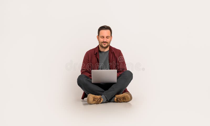 Full length of handsome entrepreneur checking e-mails over laptop while sitting on white background. Full length of handsome entrepreneur checking e-mails over laptop while sitting on white background.