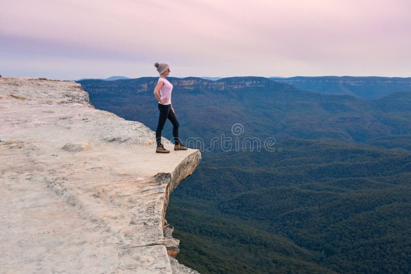 Положение Hiker на уступе горы смотря вне к долине за пределами стоковое изображение Положение Hiker на уступе горы смотря вне к долине за пределами стоковое изображение