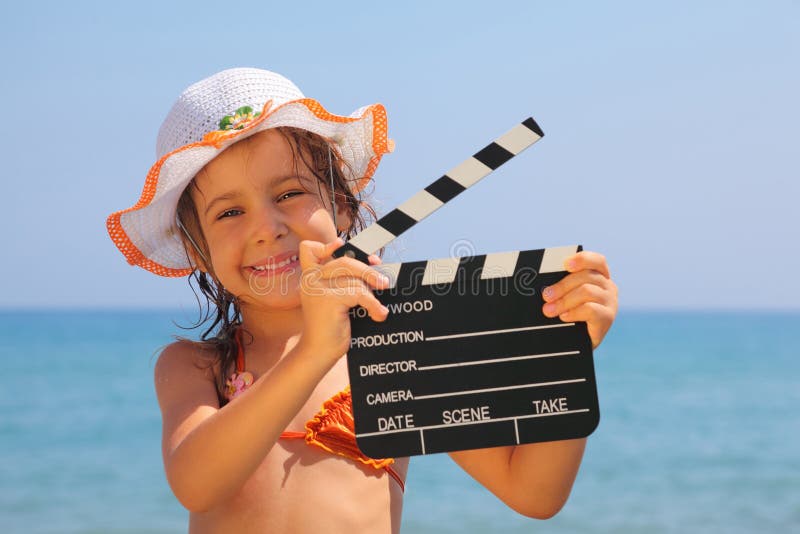 положение удерживания девушки clapboard пляжа стоковое фото rf положение удерживания девушки clapboard пляжа стоковое фото rf